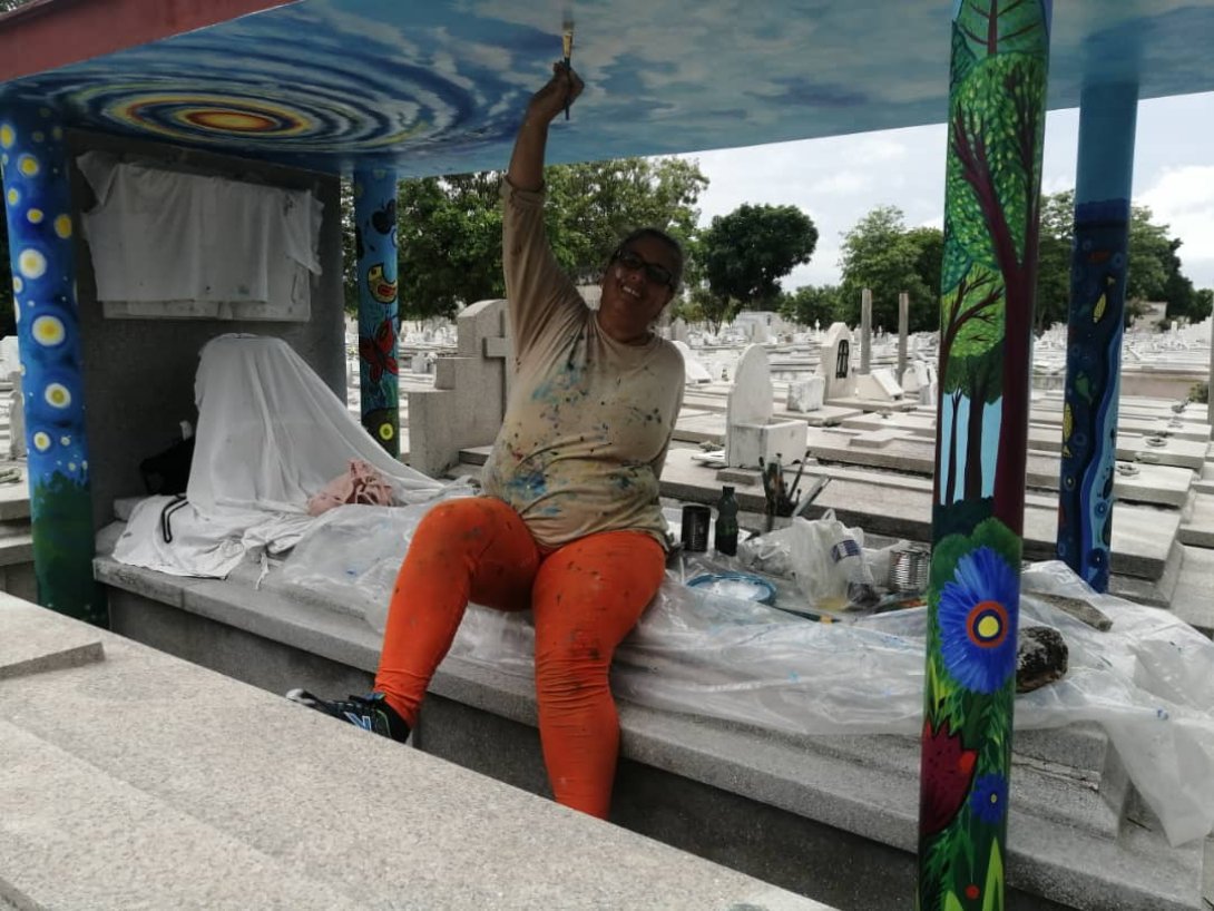 La artista cubana Marnia Briones pintando en un cementerio.