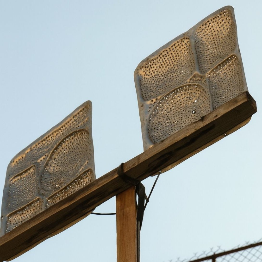 Antena improvisada hecha con bandejas metálicas perforadas, montada sobre un poste de madera bajo el cielo despejado.
