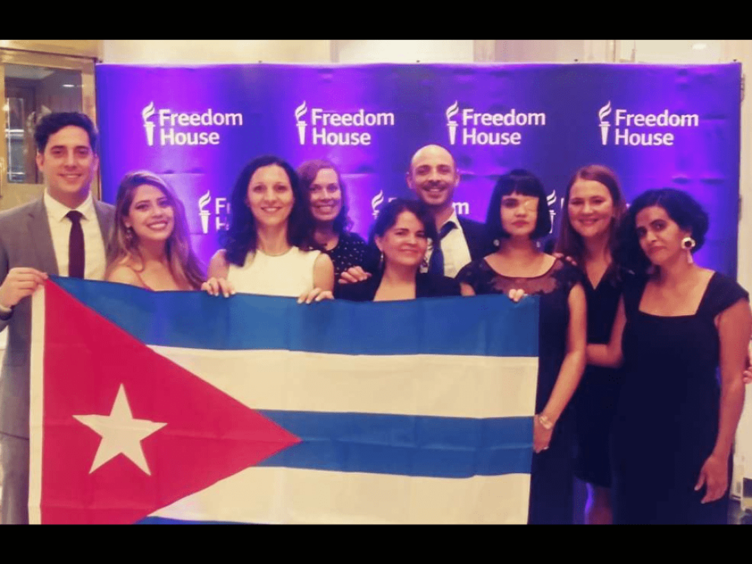 Anamely Ramos sostiene una bandera cubana junto a otros representantes del MSI durante la premiación.
