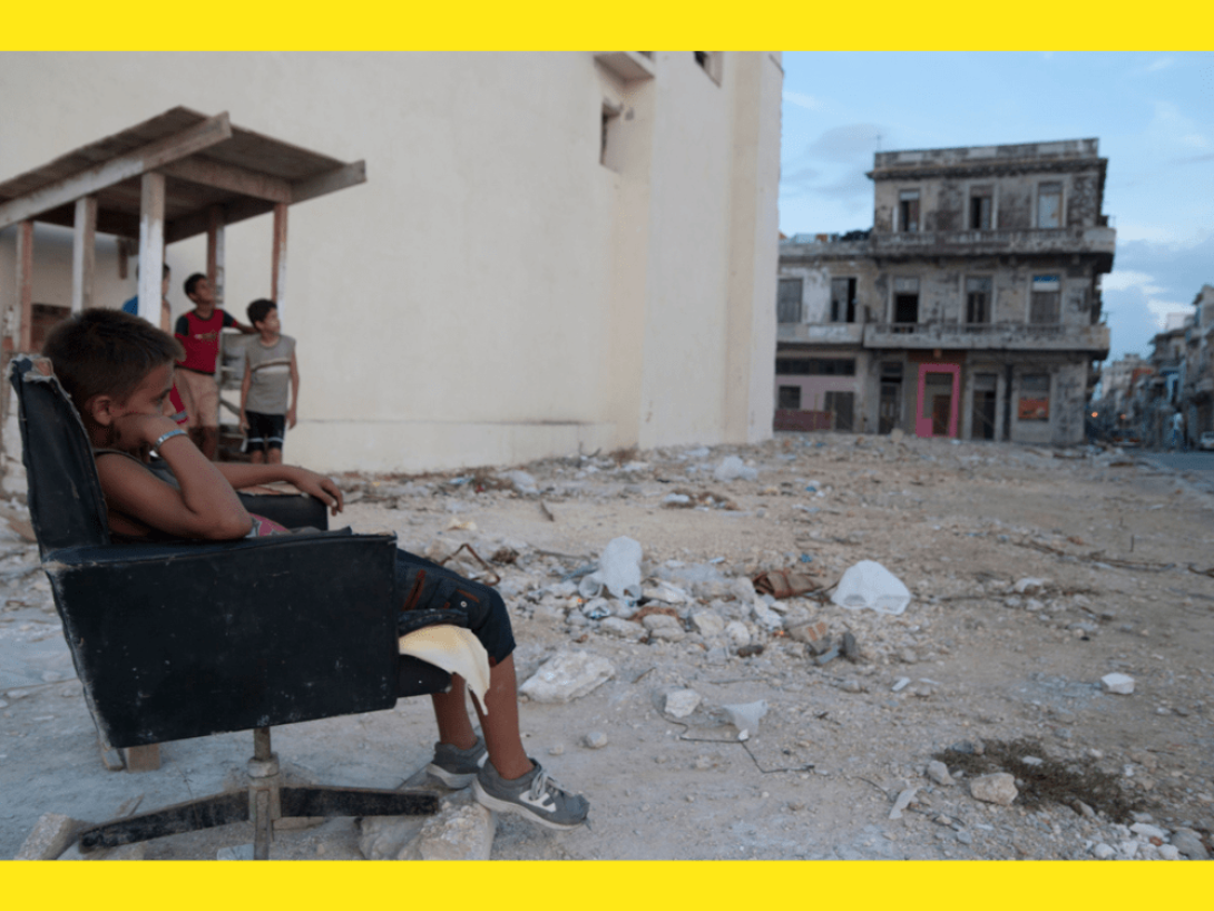 Niños sentados entre los escombros en Cuba.