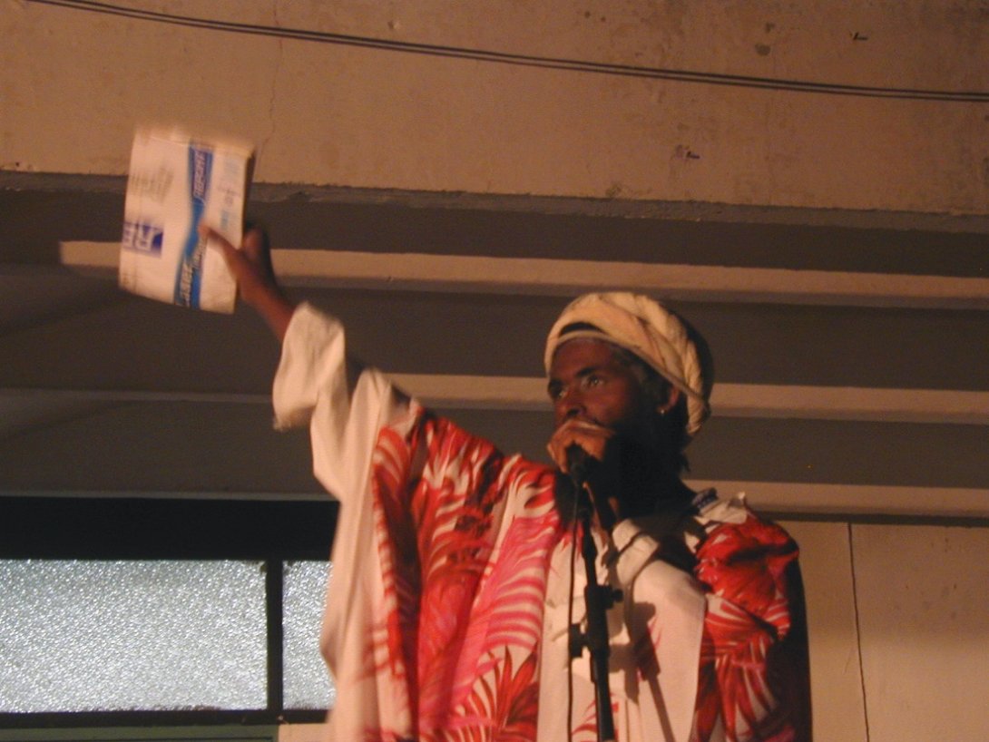 Amaury pacheco frente a un micrófono con un libro en alto