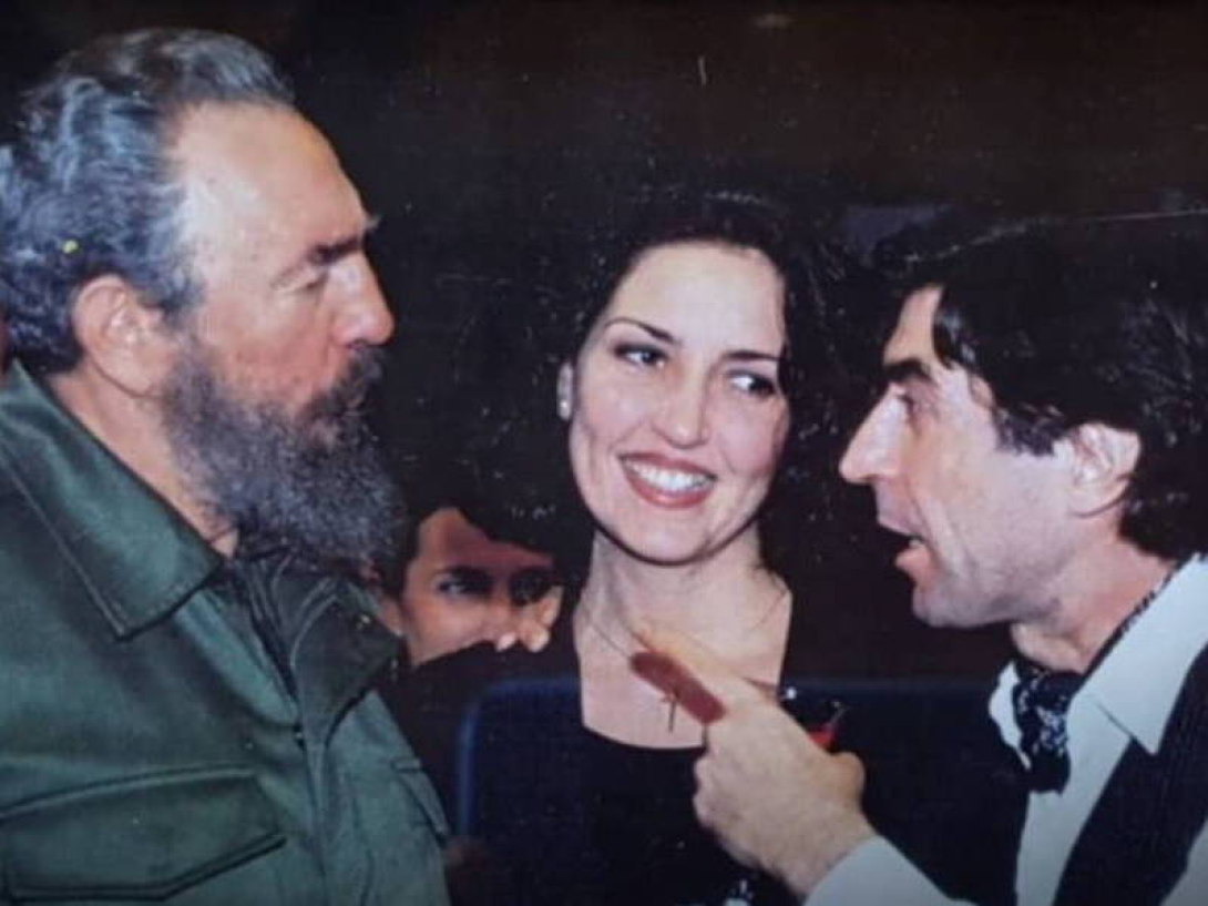 Joaquín Sabina y Fidel Castro hablando, una mujer al centro.