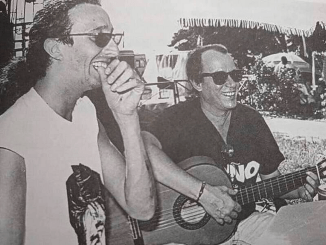 Fito Páez riendo junto a Silvio Rodríguez con guitarra en mano.