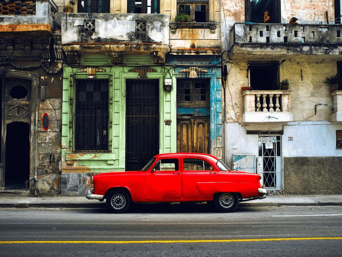 Auto antiguo parqueado frente a edificios viejos en La Habana, Cuba.