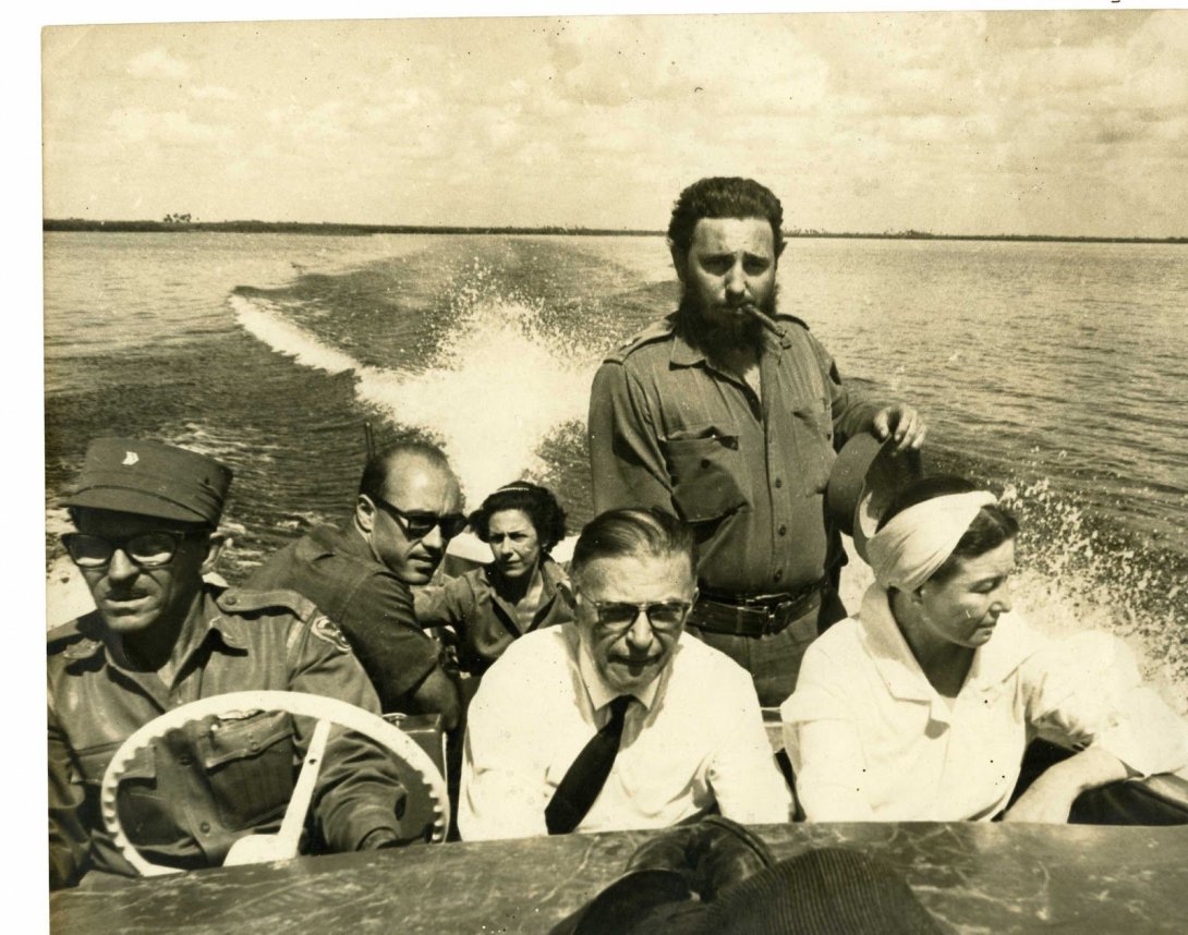 Varias personas a bordo de una lancha navegando. Se ven cinco sentadas, Fidel de pie.