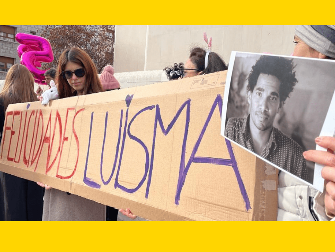 Cubanos despliegan un cartel donde se lee "Felicidades Luisma" junto a una foto del artista cubano para protestar en Madrid durante su cumpleaños.