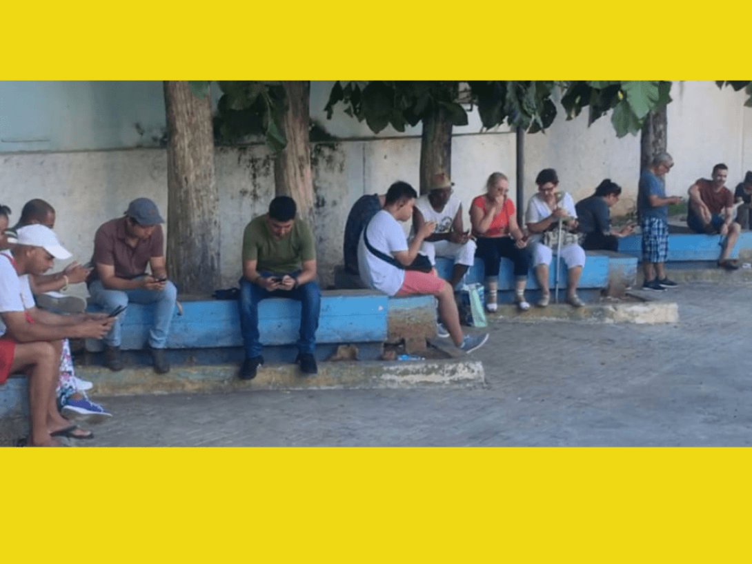 Personas sentadas en un parque en Cuba para acceder a internet a través de la WiFi.