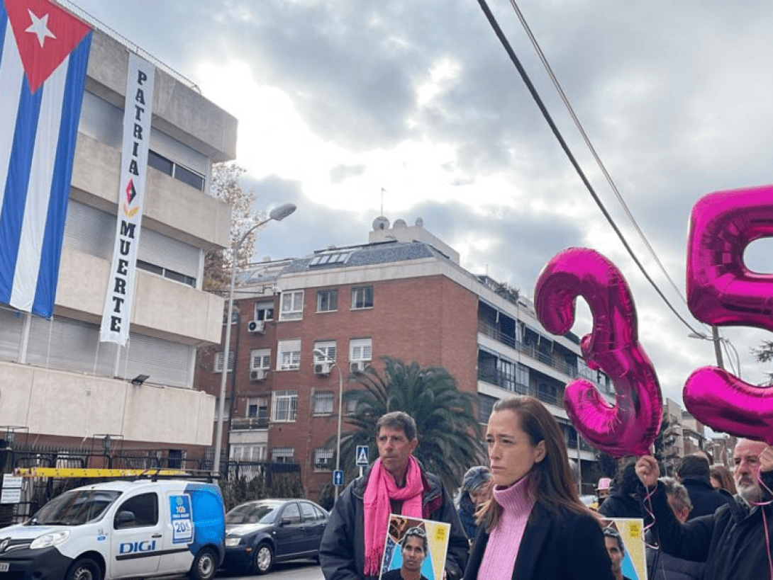 Protestas fuera del Consulado cubano en España recuerdan al artista cubano preso político en su cumpleaños 35 con globos, fotos y otras alegorías. Detrás, la bandera cubana.