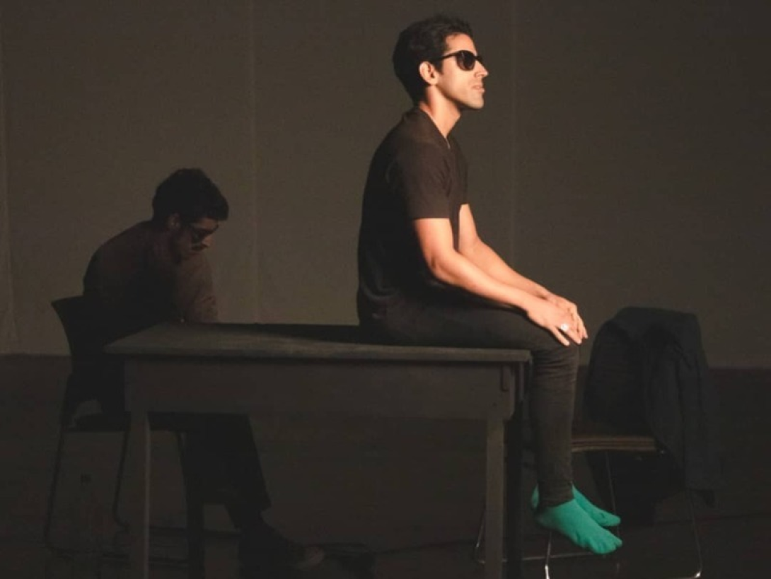 Lázaro Saavedra durante la puesta en escena de "Normalización": el actor con los ojos tapados está sentado sobre una mesa.