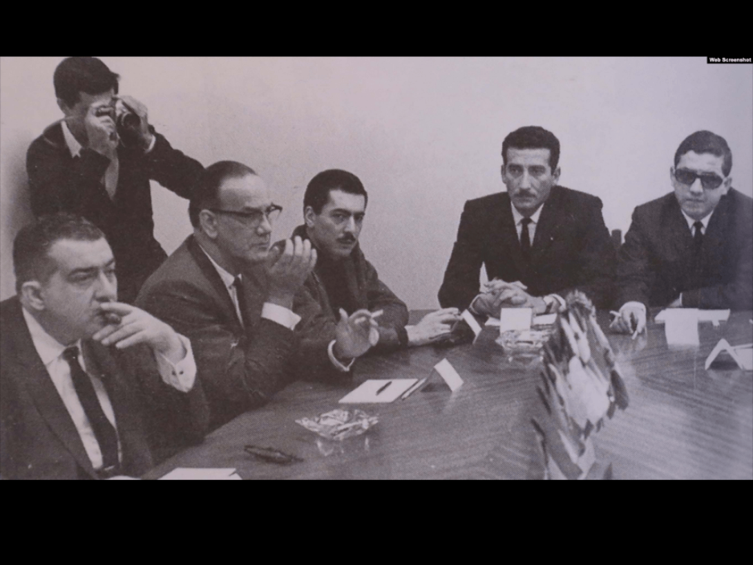 Sentado a una mesa, con intelectuales y artistas cubano, Mario Vargas Llosa.