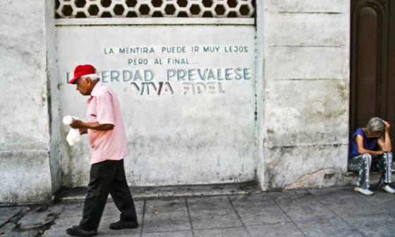 Calle de La Habana con consigna, anciano cruza