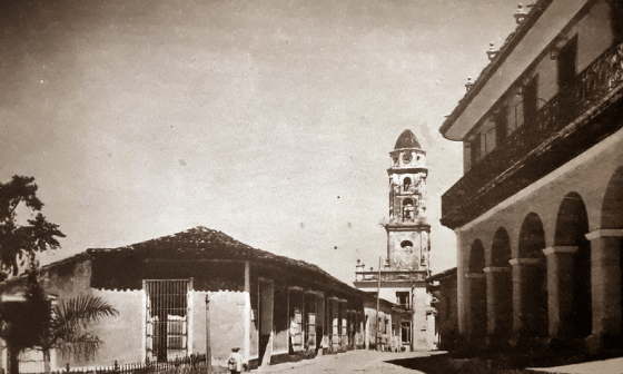 Foto antigua de la ciudad de Trinidad en Cuba: una calle que conduce al la torre insignia de la villa entre casonas coloniales.