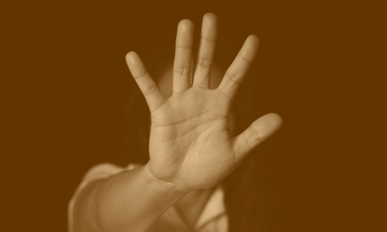 Contra la violencia hacia la mujer: Mujer pone su mano delante en señal de "stop".