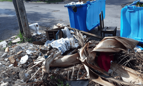 Contenedores de basura rotos y desbordados de desperdicios en la calle.