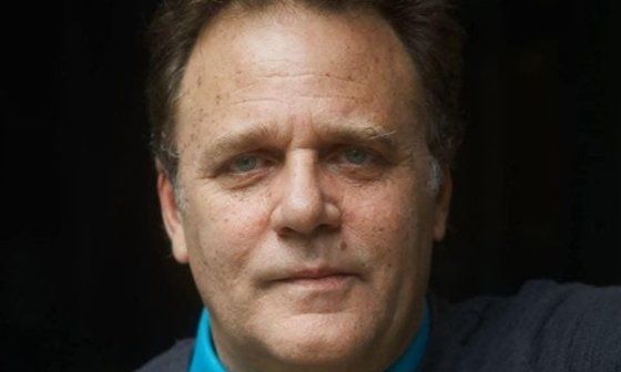 Retrato de Mauricio Rentería, actor y director de teatro, mirando a cámara, plano medio con fondo oscuro.