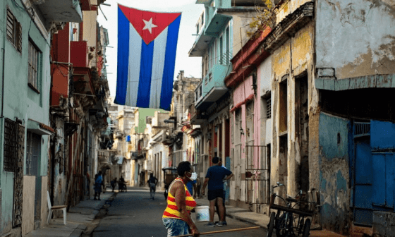 Calles de Cuba: pobreza, basura y una bandera cubana colgada en el centro.