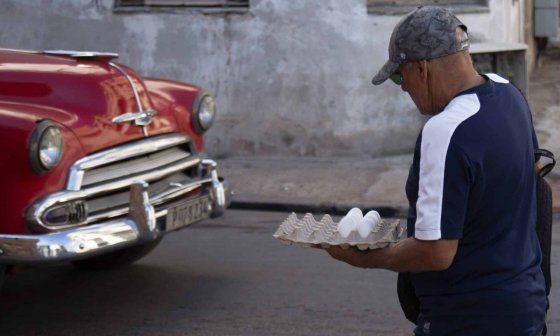 Un cubano camina con un cartón de huevos.
