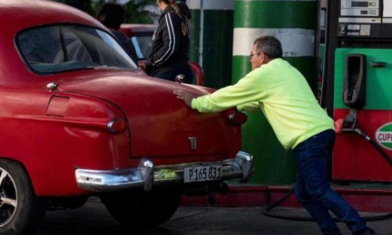 Cubano empuja su auto en una gasolinera.