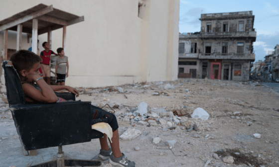 Niños sentados entre los escombros en Cuba.