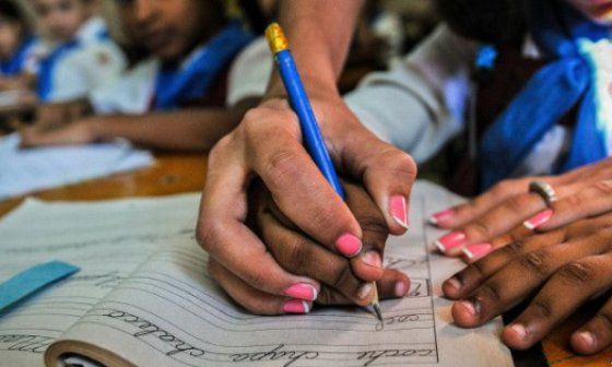 Maestra enseña a un niño cubano a escribir