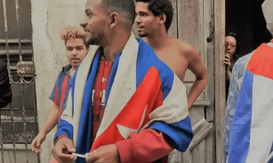 Personas en la calle con una bandera cubana. 