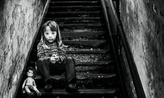 Niña sentada en una escalera junto a su muñeca.