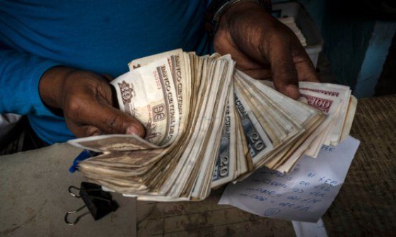 Una persona sostiene decenas de billetes de pesos cubanos.