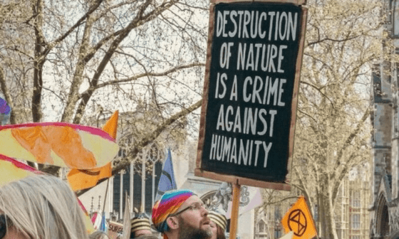 Activista sosteniendo un cartel donde se lee: "Destruction of nature is a crime against humanity" (la destrucción de la naturaleza es un crimen contra la humanidad).