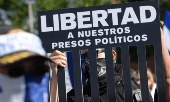 Personas manifestándose alzan un cartel por la libertad de los presos políticos en Nicaragua.